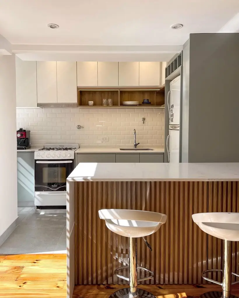 Cocina de departamento con barra revestida en listones de madera y banquetas