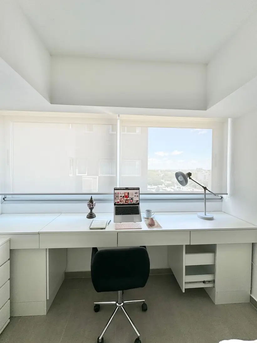 Escritorio blanco largo bajo la ventana con cajones a ambos lados