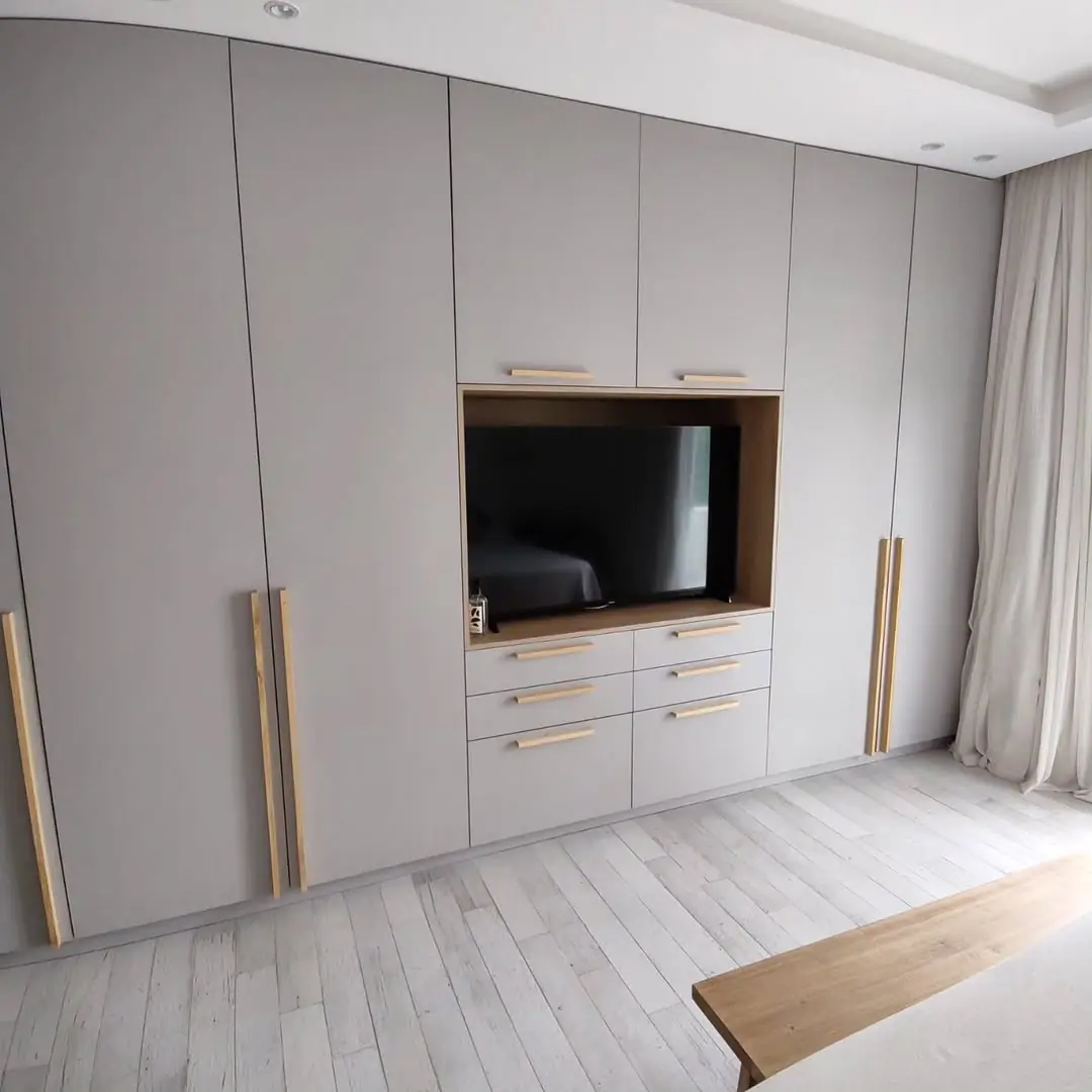 Placard gris de pared completa con nicho de TV embutido y tiradores verticales de madera