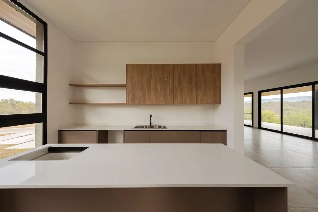 Cocina en tono topo con alacena de madera frente a un ventanal