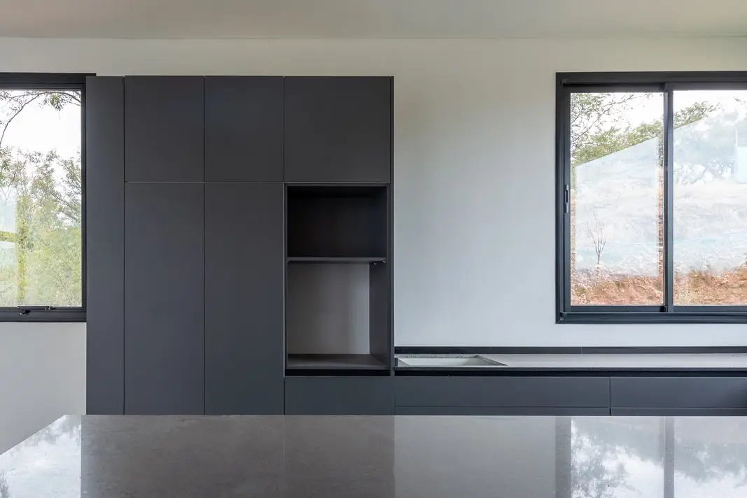 Mueble de cocina negro mate con nicho para horno y mesada de granito