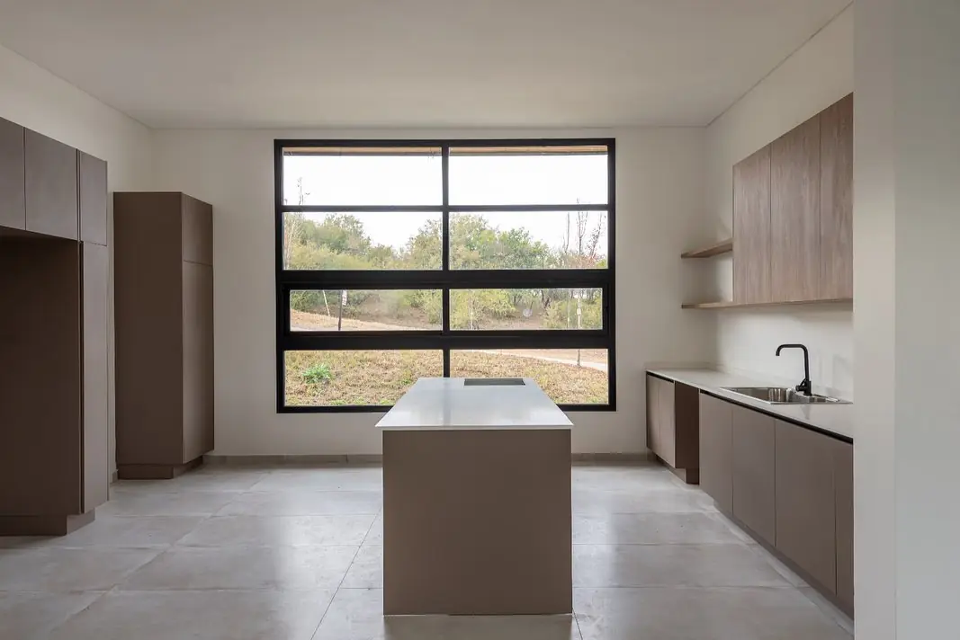 Cocina en tono topo con columnas de piso a techo e isla central